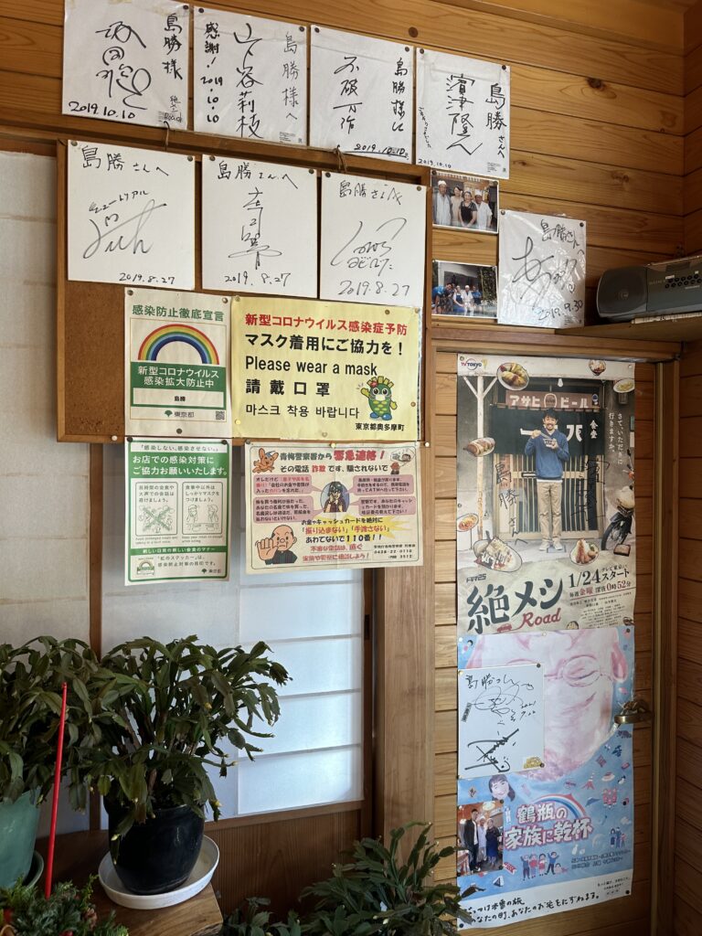 島勝：お店の入り口右側に飾ってある色紙やポスター類